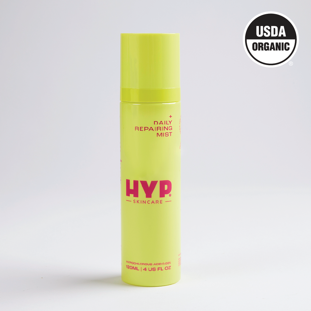 A standalone image of a bright yellow bottle of 'HYP Daily Repairing Mist' set against a plain white background. The product is labeled with the brand name 'HYP' in large pink letters and the words 'Daily Repairing Mist' above it. The 'USDA ORGANIC' seal is visible in the upper right corner of the bottle, certifying its organic status.